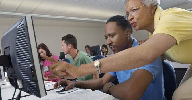 Teacher helping student in computer class
