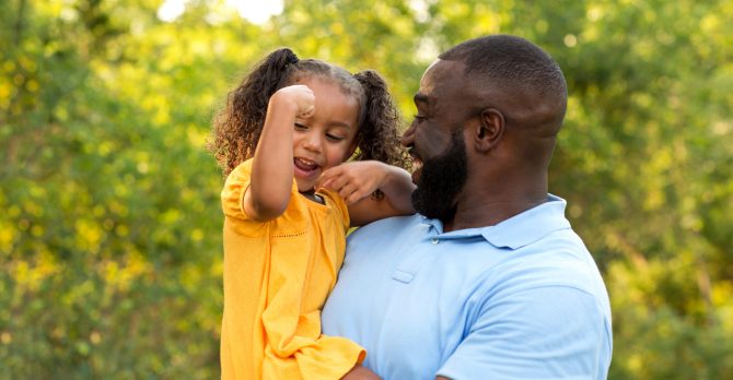Father and his daughter laughing and playing outside.